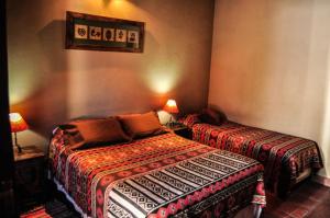 Habitación con 2 camas y mesa con lámpara. en Casagrande Hotel de Adobe en Tinogasta