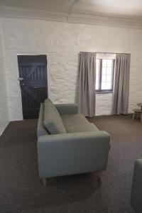 a couch in a room with a door and a window at Paxton Square Cottages in Burra