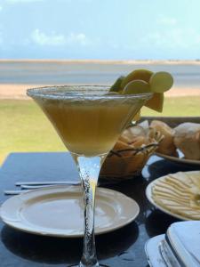 a martini glass on a table with a plate of food at Pousada Portal da Ilha in Itarema