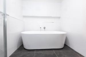 a white bath tub in a bathroom with a shower at 4 Bedroom Inner City Townhouse - SLEEPS 9 !! in Wagga Wagga
