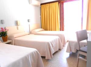 a hotel room with three beds and a window at Hotel Tramontana in Benicàssim