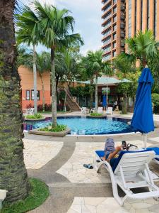 un hombre tendido en una silla de playa en una silla de jardín junto a una piscina en KL Service Suites at Times Square KL, en Kuala Lumpur