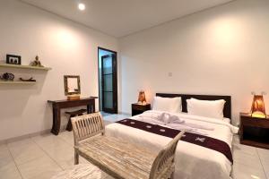 1 dormitorio con cama grande y banco de madera en Clover Villa Sanur, en Sanur 14 fotos más