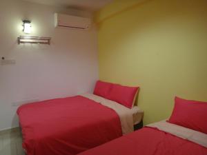 two beds in a small room with red sheets at Famosa 2 Stay in Malacca