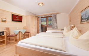 eine Reihe von Betten in einem Zimmer mit einem Tisch und Stühlen in der Unterkunft ApartHotel Holzerhof in Schladming