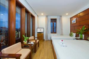 a hotel room with a bed and a living room at Kiman Hoi An Hotel in Hoi An