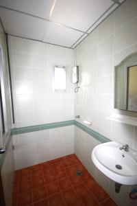 a white bathroom with a sink and a mirror at Matini Amata in Ban Hua Phai