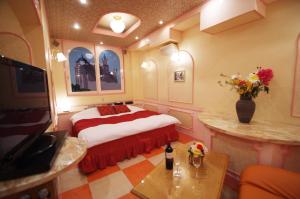 - une chambre avec un lit et un vase de fleurs dans l'établissement Alohain Yonago, à Yonago