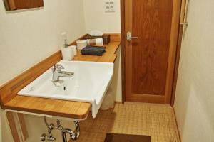 Kyoto Machiya Saikyo-Inn في كيوتو: حمام مع حوض أبيض وطاولة خشبية