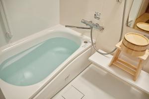 Kyoto Machiya Saikyo-Inn في كيوتو: حوض استحمام أبيض في حمام مع مقعد