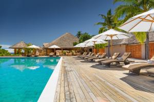 a pool at a resort with lounge chairs and umbrellas at Kudafushi Resort & Spa in Raa Atoll