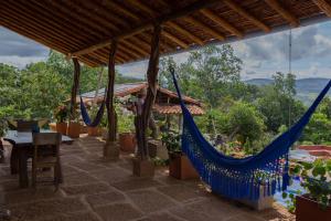a patio with a hammock and a table with plants at Casa Upa ,casa con piscina espectacular, Barichara in Barichara