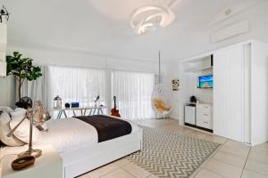 a white bedroom with a large bed and a rug at La Boheme Whitsunday in Airlie Beach