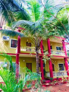 a building with a palm tree in front of it at Laliguras Villa Beachside Escape - 100m from Candolim Beach in Candolim
