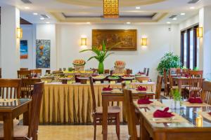 a restaurant with tables and chairs and a buffet at Kiman Hoi An Hotel in Hoi An