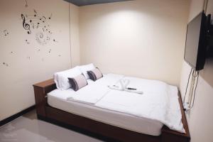 a bedroom with a bed with white sheets and a tv at Khaosan Station in Bangkok