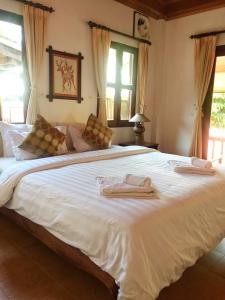 a bedroom with a large white bed with towels on it at Villa Sayada in Luang Prabang