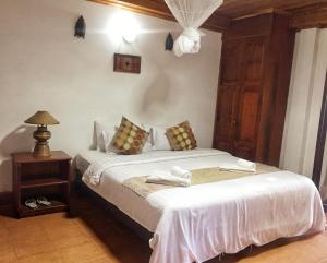 - une chambre avec un lit et une table de nuit avec une lampe dans l'établissement Villa Sayada, à Luang Prabang