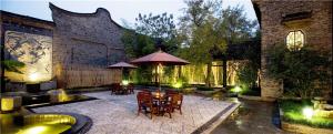 a patio with tables and chairs and an umbrella at Wuzhen Clubhouse (In Xizha Scenic Area - ticket included) in Tongxiang