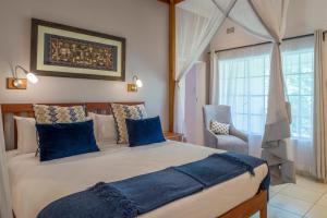 a bedroom with a large bed with blue pillows and a chair at Batonka Guest Lodge in Victoria Falls