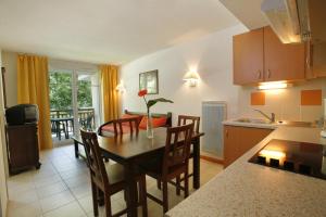 - une cuisine et une salle à manger avec une table et des chaises dans l'établissement Résidence VTF Les Allées du Green, à Levernois