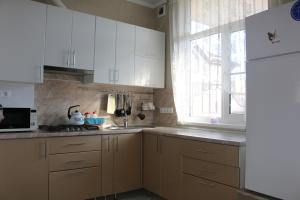 ゲレンジークにあるКвартира для отдыхаの白いキャビネット、シンク、窓付きのキッチン