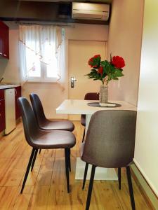 a table with chairs and a vase with red flowers at Apartment Lovre in Split