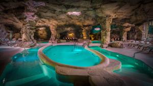 a swimming pool in a cave with a rock wall at Tombolo Talasso Resort in Marina di Castagneto Carducci