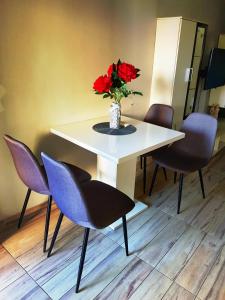 a white table with a vase of red flowers on it at Apartment Lovre in Split