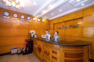 dos personas de pie en un mostrador en una habitación con relojes en Bon Ami Hotel - Thiên Xuân Hotel, en Ho Chi Minh