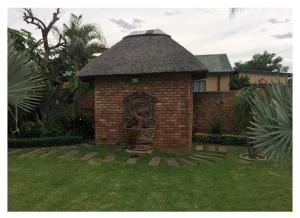 a brick building with a statue in a yard at Lala Bela Guest House in Bela-Bela