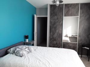 1 dormitorio con cama blanca y pared azul en Petite suite sympa Avoine, en Avoine