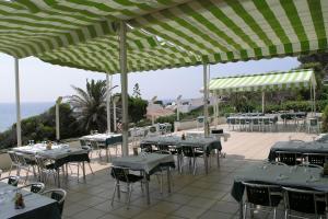 a restaurant with tables and chairs under green umbrellas at Hotel Llorca in Platja de l’Almadrava