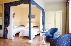 a bedroom with two beds with blue curtains and a chair at Residence Liberty in Trieste
