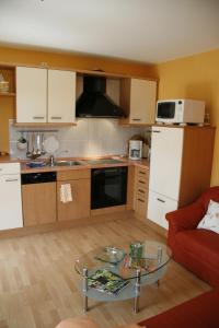 eine Küche mit einem roten Sofa und einem Glastisch in der Unterkunft Ferienwohnung Klabautermann in Putbus