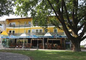 a yellow building with tables and chairs in front of it at Hotel Promenade in Bad Füssing