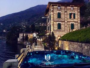 a swimming pool in front of a building next to the water at Villa Marina - Como lake in Bellano