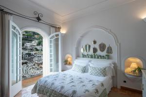 um quarto com uma cama branca e 2 janelas grandes em Casa Buonocore em Positano