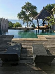 a swimming pool with two benches and a gazebo at Villa Bella Vista in Nusa Lembongan