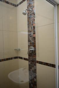 a shower with a glass door and a sink at Tudor House Hotel in Durban