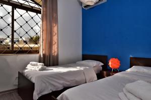 twee bedden in een kamer met blauwe muren en een raam bij City Living Suite TK 1 Rm 1 in St Julian's