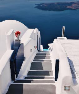 uma escada que leva ao oceano azul em Katikies Chromata Santorini - The Leading Hotels of the World em Imerovigli