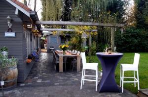 B&B Het Brembos في Wingene: فناء مع طاولة وكراسي وبيرغولا