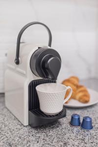 a coffee maker with a cup and a plate of croissants at APARTEL Plac Zbawiciela in Warsaw