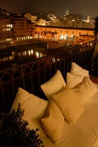 un letto bianco con cuscini su un balcone di notte di Hotel degli Orafi a Firenze