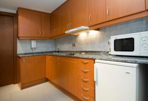 cocina con armarios de madera y microondas blanco en Apartamentos Turísticos Roc Del Castell, en Canillo
