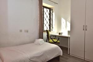 een slaapkamer met een bed, een stoel en een raam bij City Living Suites TK1 Rm 2 in St Julian's
