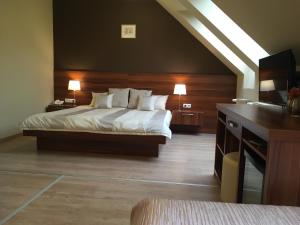 a bedroom with a bed and a desk with two lamps at Alfa Hotel in Győr