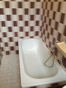 eine Badewanne im Bad mit einer gefliesten Wand in der Unterkunft AT Pension in Budweis