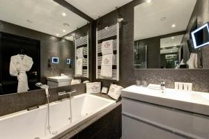 a bathroom with a tub and a sink and a mirror at The Pavilions Amsterdam, The Toren in Amsterdam